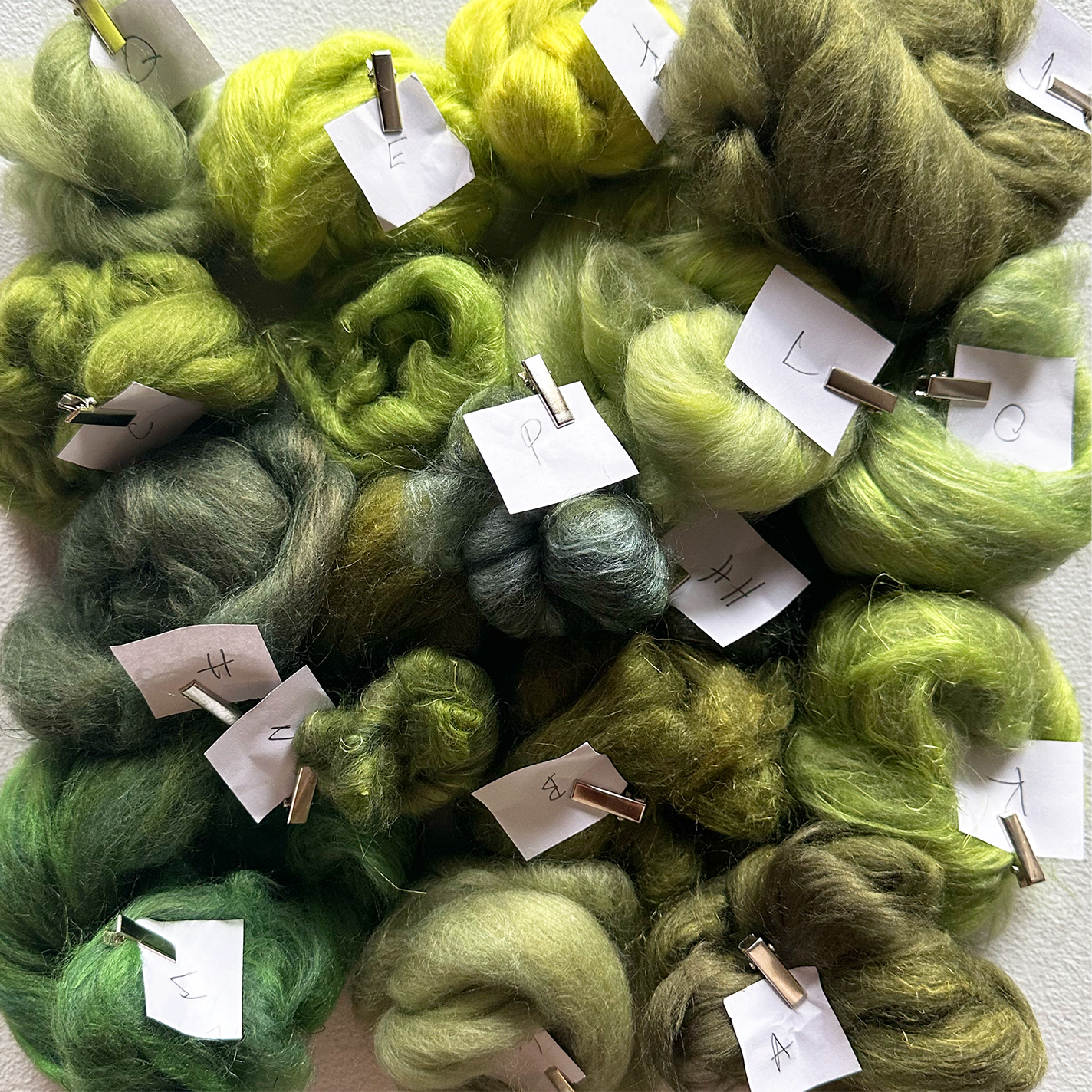 Hand-carded green fiber bundles for color sampling.
