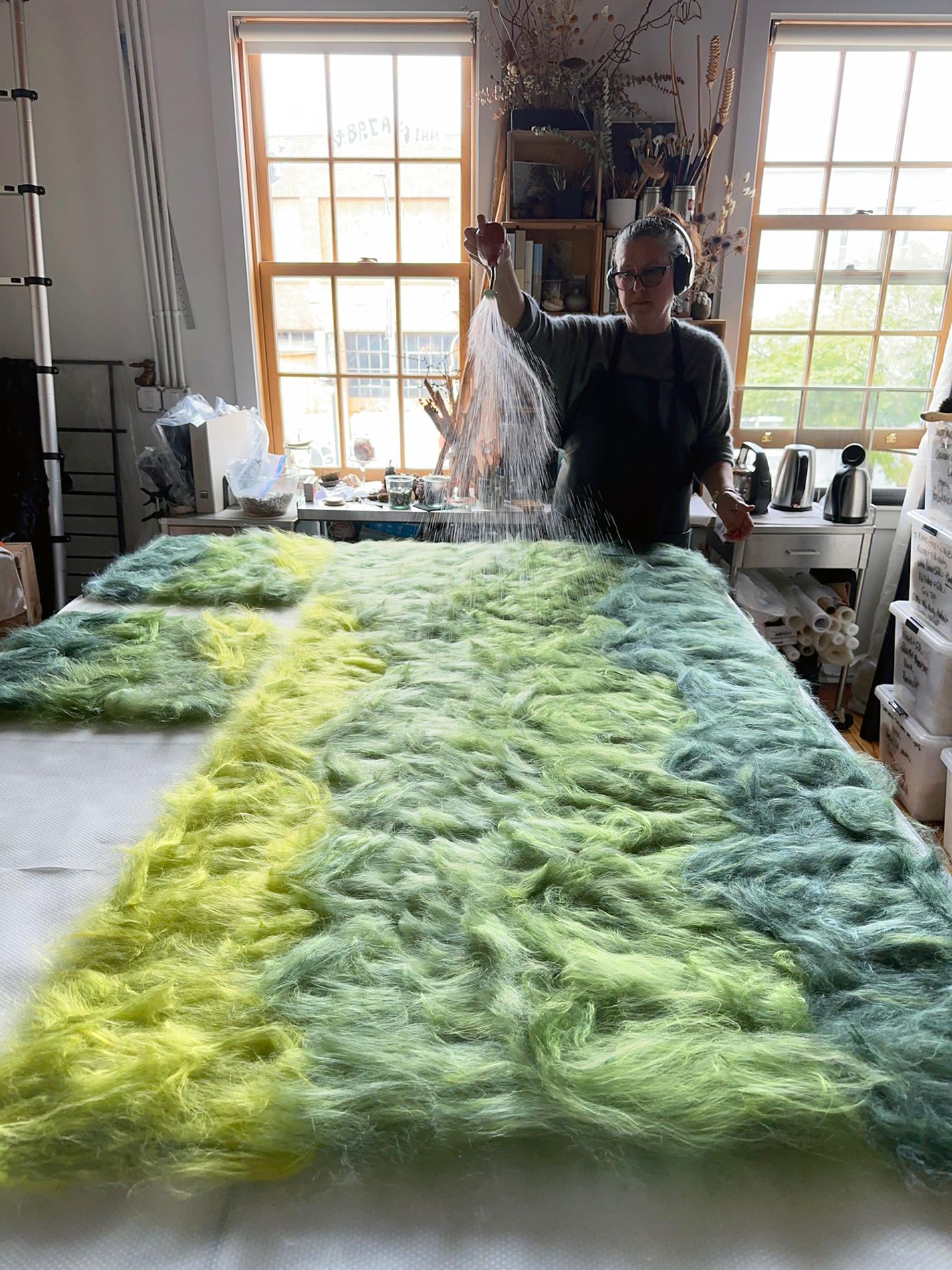 Colombano sprinkles a large green-dyed wool pile with water