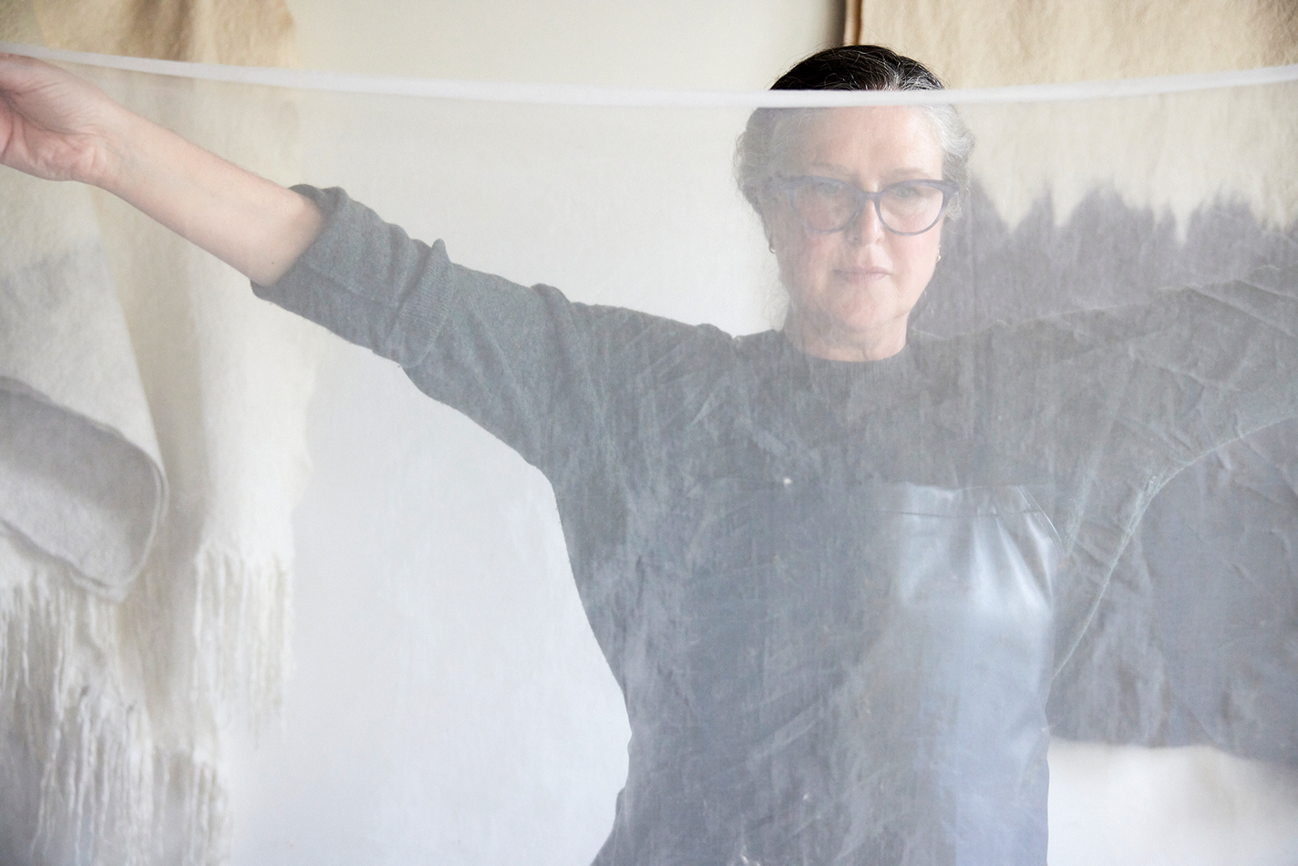 Colombano holds up the fine netting she uses to secure fibers while felting.