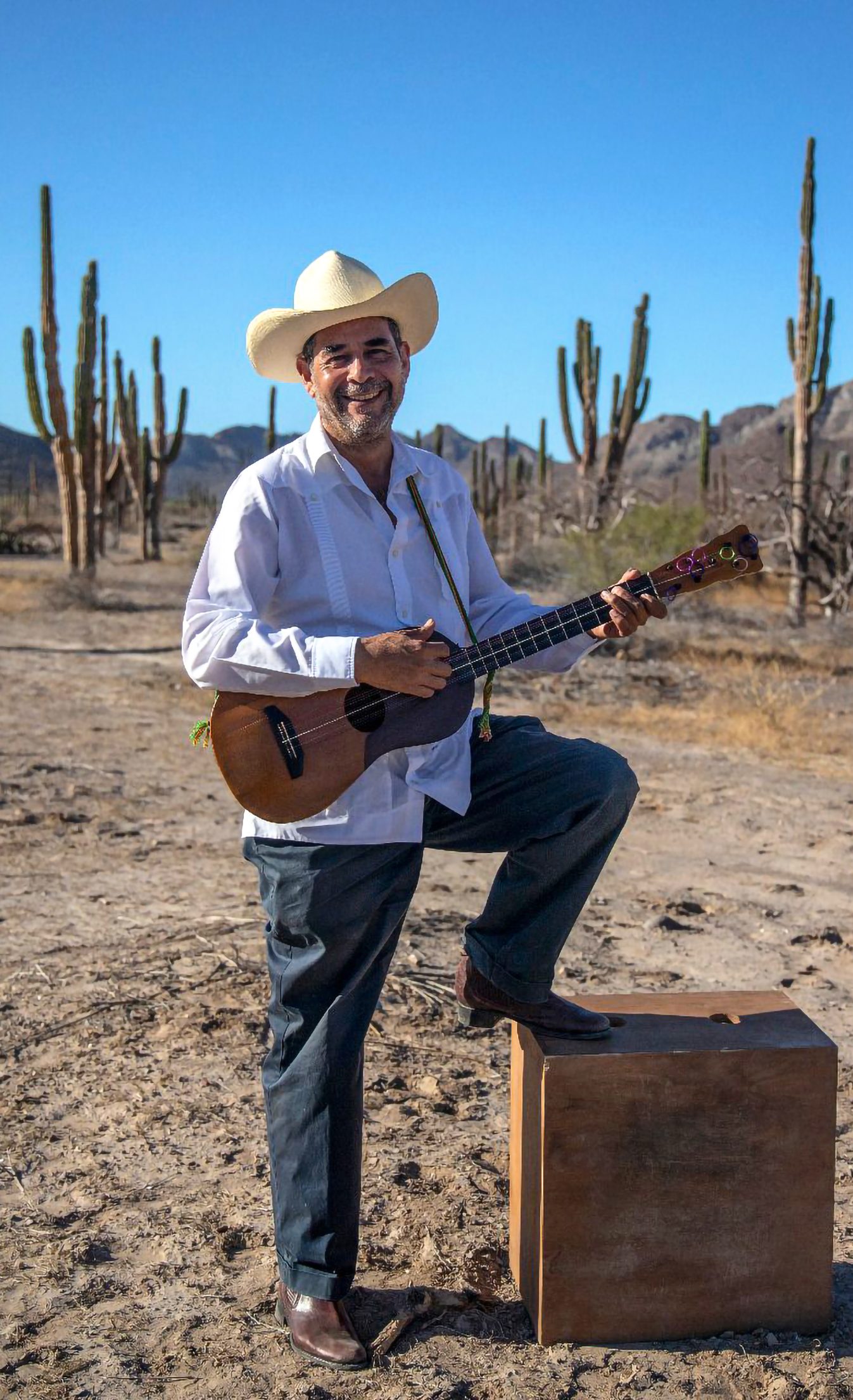 Gilberto Gutiérrez poses in the desert holding an instrument.