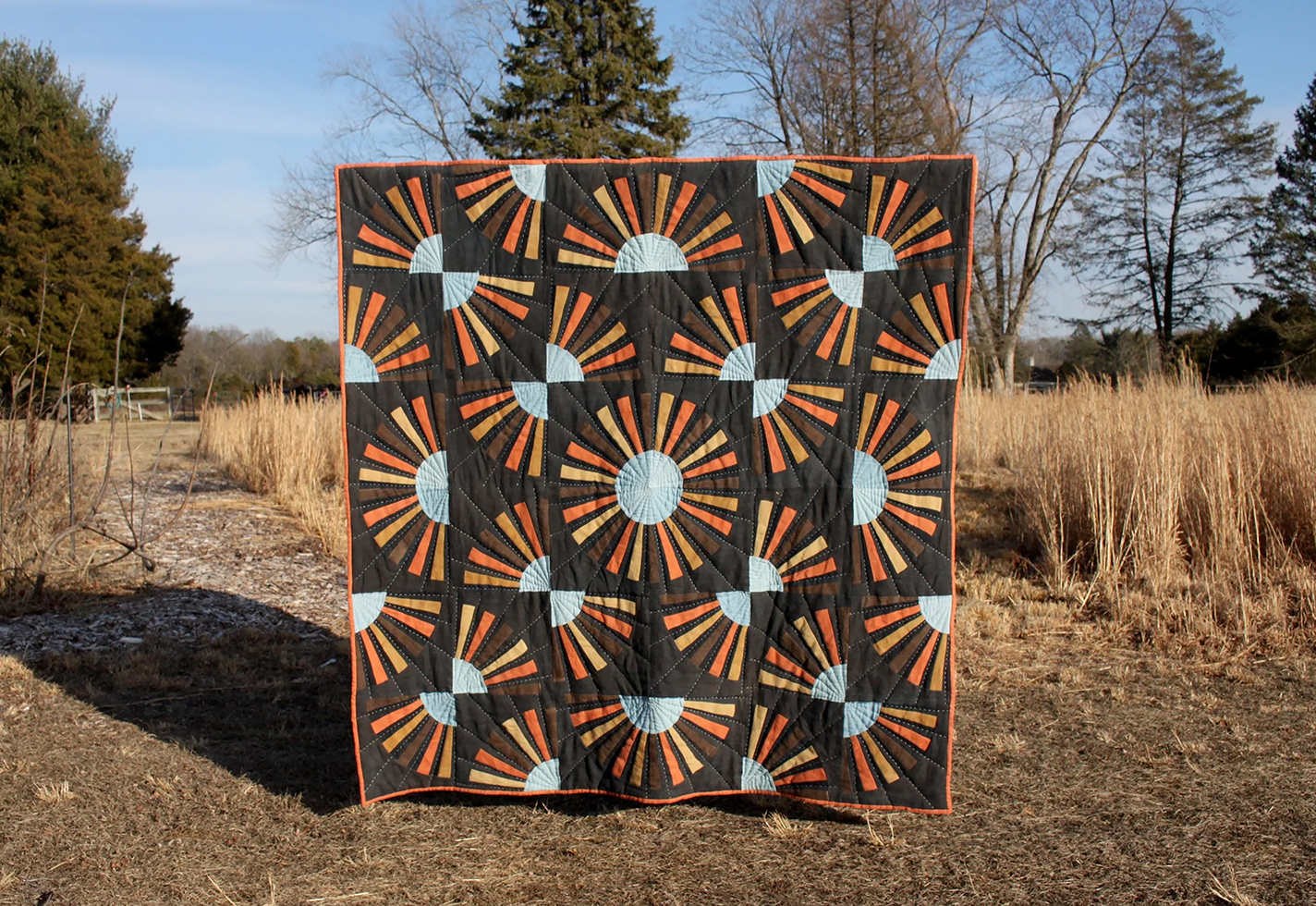 Large hand-dyed quilt held up in a field of grasses