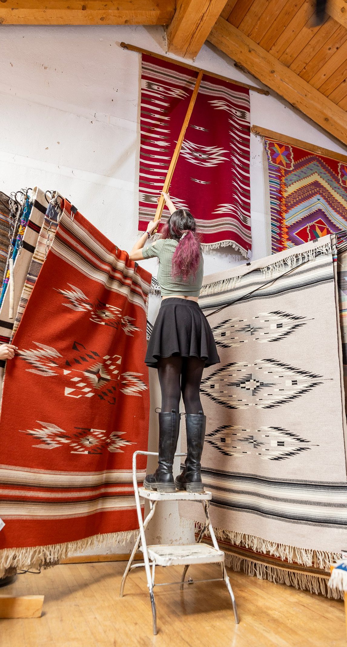 Eighth-generation weaver Emily Trujillo hangs a tapestry at Centinela Traditional Arts, her family’s gallery in Chimayo, New Mexico.