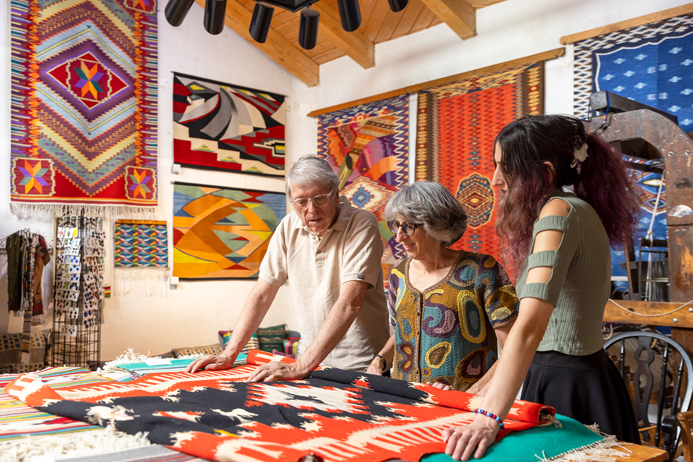 Emily Trujillo pores over an 1800s weaving with her parents, Irvin and Lisa.