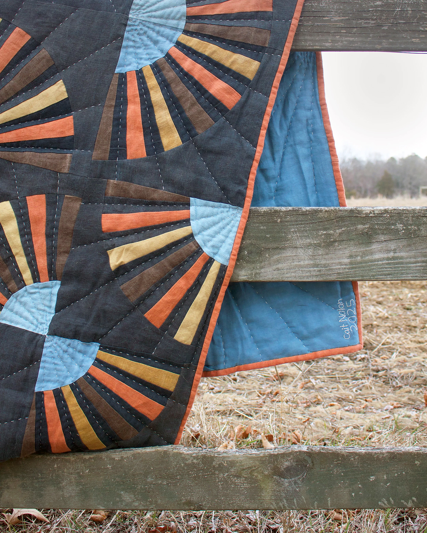 Quilt draped over a wooden fence
