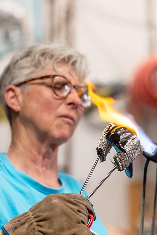 Holmes heats a glass bird with a torch.